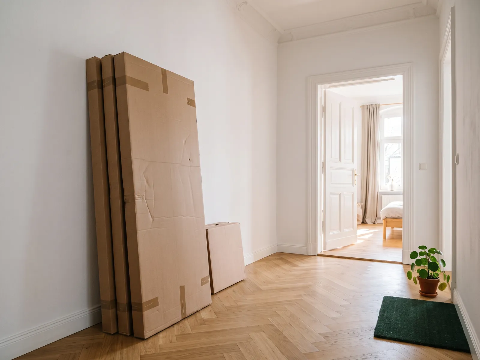 Flach verpackte Kleiderschrank-Kartons im hellen Flur einer Altbauwohnung